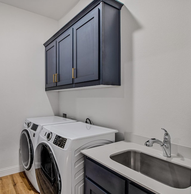 laundry room with sink, separate washer and dryer, light hardwood / wood-style floors, and cabinets