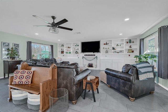 living room featuring built in shelves, a healthy amount of sunlight, ceiling fan, and visible vents