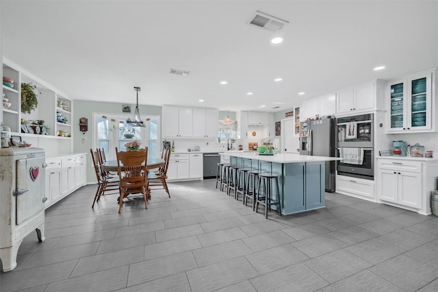 kitchen featuring appliances with stainless steel finishes, white cabinets, and visible vents