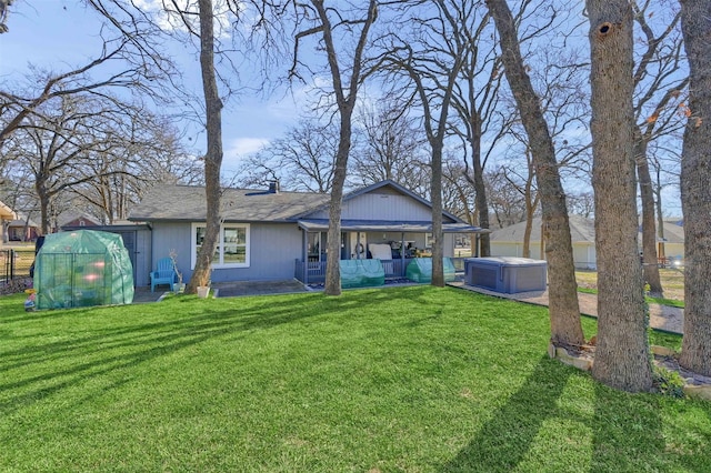 back of property with a greenhouse, a lawn, an outdoor structure, and a patio area