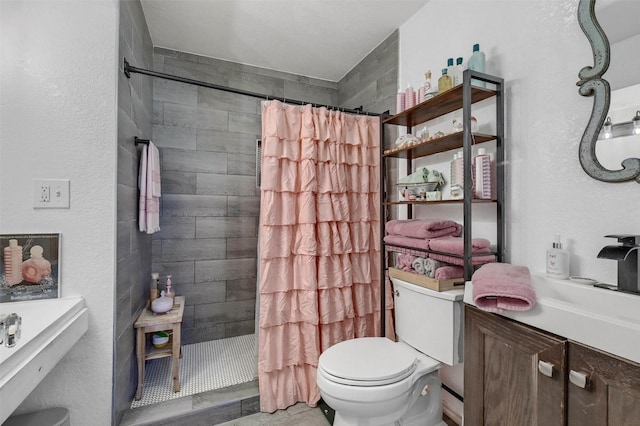 bathroom featuring vanity, a tile shower, and toilet