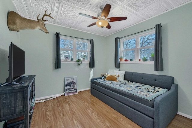 living area featuring a healthy amount of sunlight, an ornate ceiling, baseboards, and wood finished floors