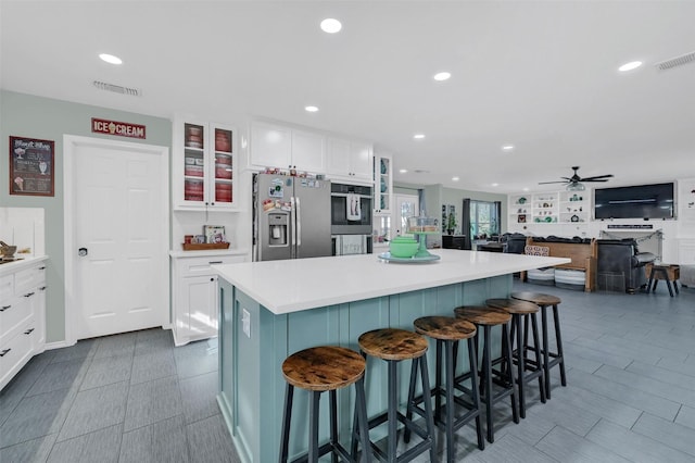 kitchen with stainless steel appliances, a center island, visible vents, and white cabinets