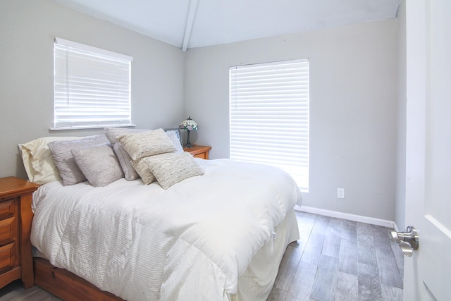 bedroom with wood-type flooring and vaulted ceiling