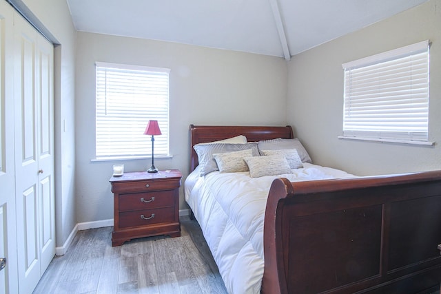 bedroom featuring vaulted ceiling, a closet, and light wood-type flooring