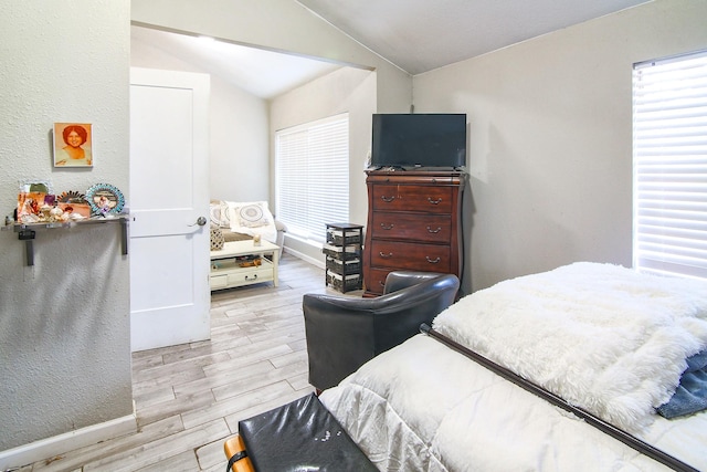 bedroom with light wood-type flooring and lofted ceiling