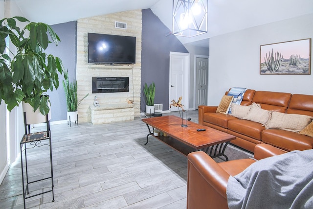 living room with light hardwood / wood-style flooring, vaulted ceiling, and a stone fireplace