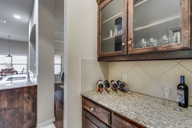 kitchen with light stone countertops, pendant lighting, dark brown cabinetry, and tasteful backsplash