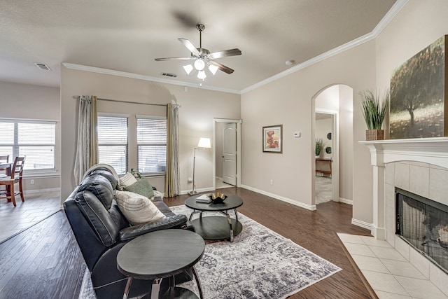 living room with light hardwood / wood-style floors, ornamental molding, ceiling fan, and a fireplace