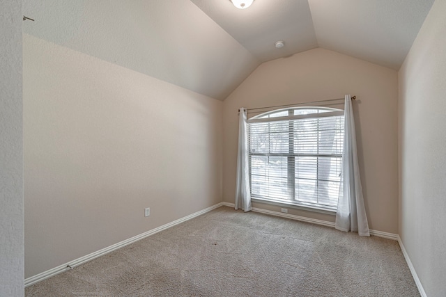 empty room with light colored carpet and lofted ceiling