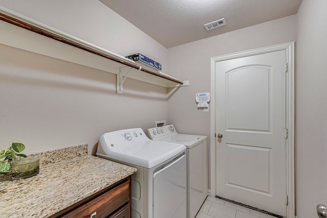 clothes washing area with a textured ceiling, light tile patterned floors, and washing machine and clothes dryer