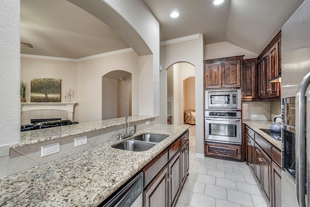 kitchen featuring appliances with stainless steel finishes, sink, ornamental molding, light stone counters, and lofted ceiling