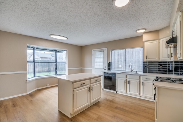 kitchen with white cabinets, a kitchen island, black dishwasher, sink, and light hardwood / wood-style flooring