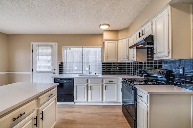 kitchen with black appliances, light stone countertops, decorative backsplash, light wood-type flooring, and sink