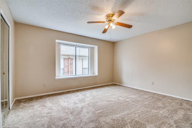 spare room with a textured ceiling, light colored carpet, and ceiling fan