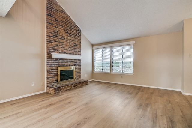 unfurnished living room with light hardwood / wood-style floors, a fireplace, a textured ceiling, and vaulted ceiling