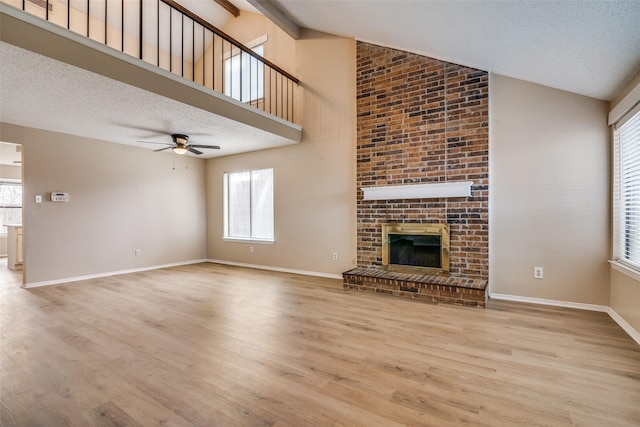 unfurnished living room featuring light hardwood / wood-style floors, a textured ceiling, vaulted ceiling, and a brick fireplace