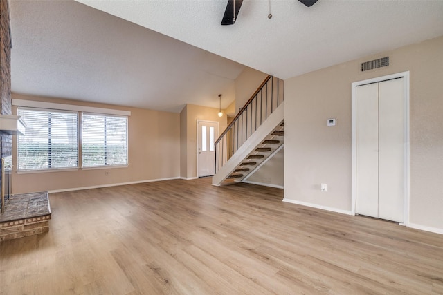 unfurnished living room featuring ceiling fan, light hardwood / wood-style floors, a textured ceiling, and lofted ceiling