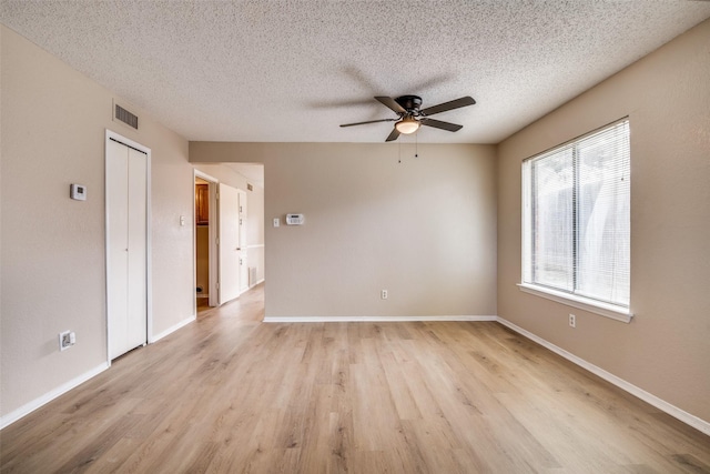 unfurnished room featuring a textured ceiling, light hardwood / wood-style flooring, a wealth of natural light, and ceiling fan