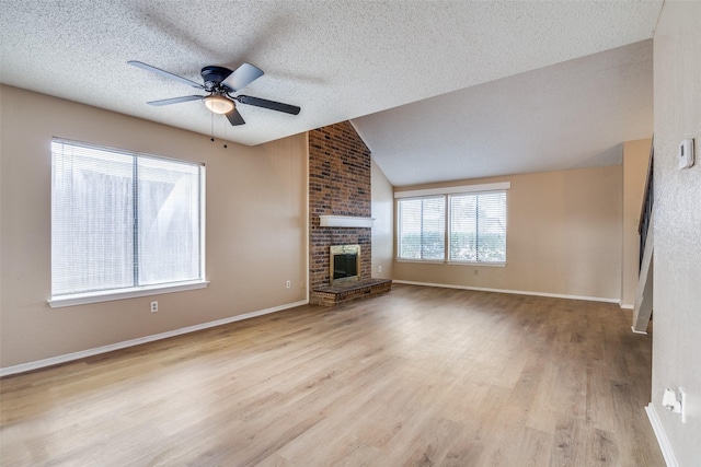 unfurnished living room with a textured ceiling, a brick fireplace, light hardwood / wood-style flooring, and lofted ceiling