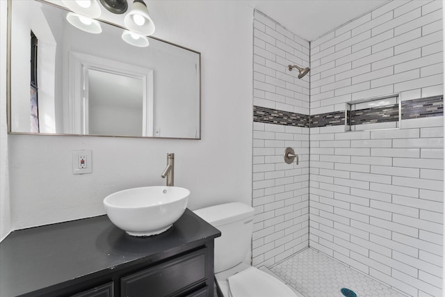 bathroom with vanity, toilet, and tiled shower