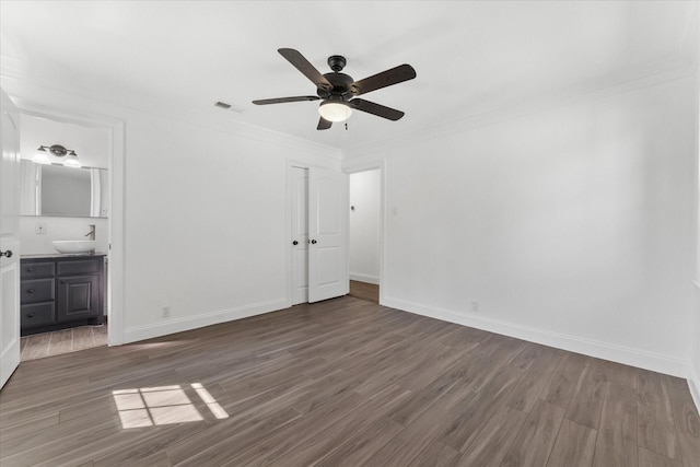 unfurnished bedroom featuring connected bathroom, sink, dark hardwood / wood-style floors, ceiling fan, and crown molding