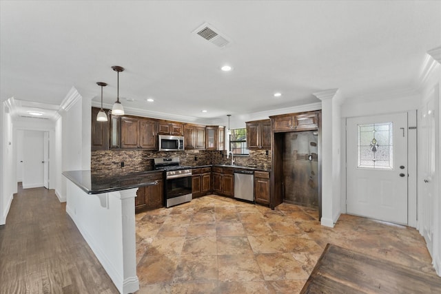 kitchen featuring crown molding, kitchen peninsula, appliances with stainless steel finishes, decorative light fixtures, and backsplash