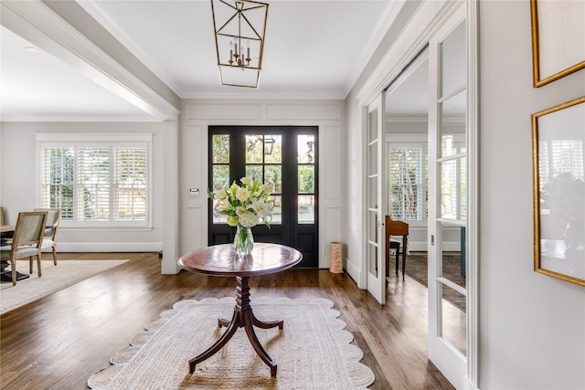 entrance foyer with crown molding, dark wood-type flooring, a notable chandelier, and french doors