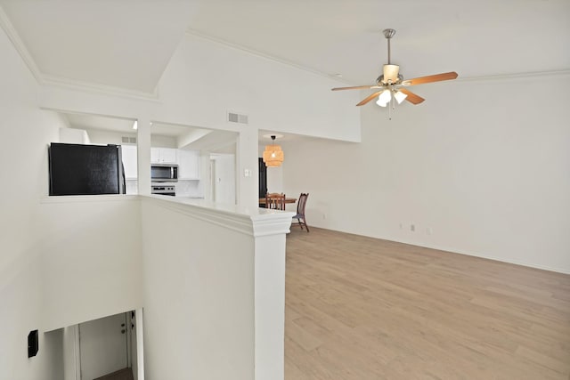 unfurnished living room with lofted ceiling, light wood-type flooring, ceiling fan, and ornamental molding