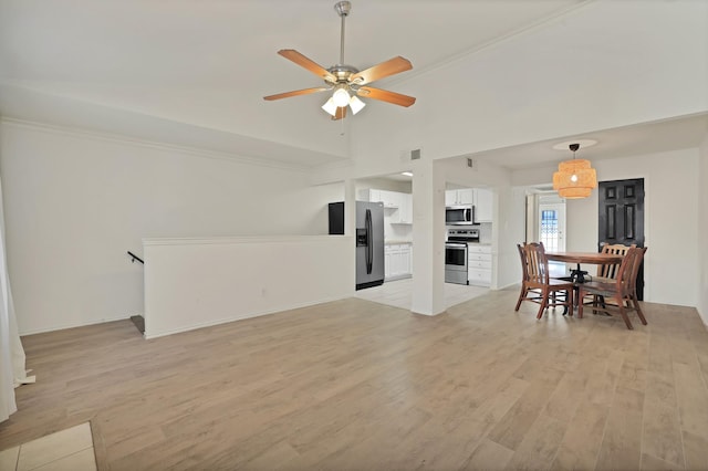 living room with ceiling fan, vaulted ceiling, and light wood-type flooring