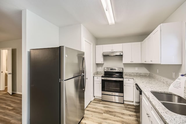 kitchen with appliances with stainless steel finishes, sink, light wood-type flooring, white cabinetry, and light stone countertops