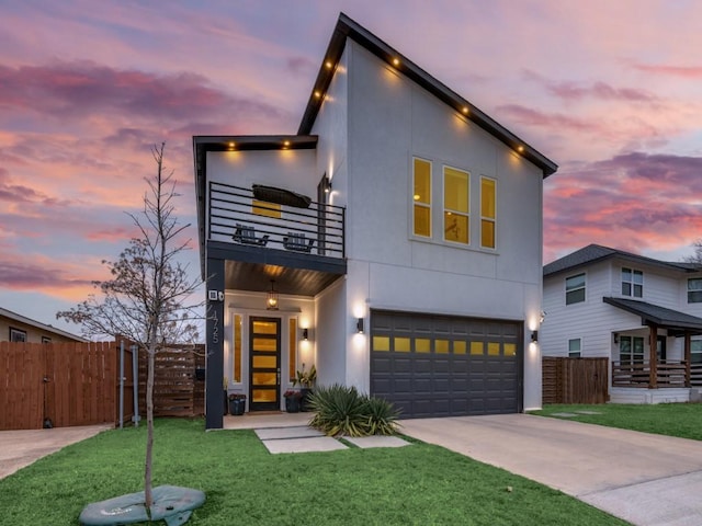 modern home featuring a balcony, a garage, and a lawn