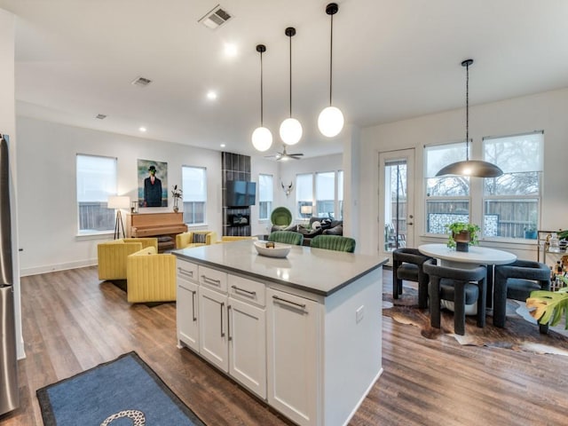 kitchen featuring decorative light fixtures, white cabinets, dark hardwood / wood-style flooring, and a kitchen island