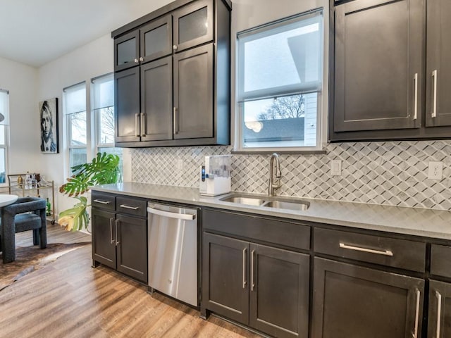 kitchen featuring sink, dishwasher, light hardwood / wood-style floors, and decorative backsplash