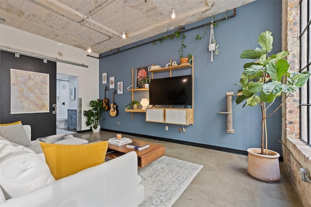 living room featuring rail lighting, concrete floors, and a barn door