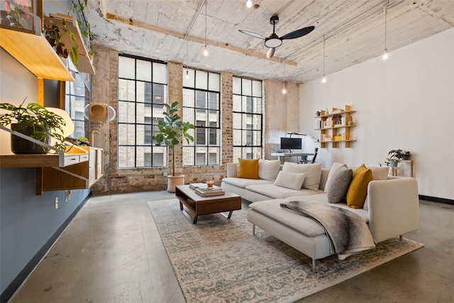 sitting room with track lighting, ceiling fan, and concrete floors