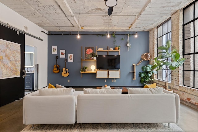 living room with track lighting, concrete floors, a healthy amount of sunlight, and a barn door