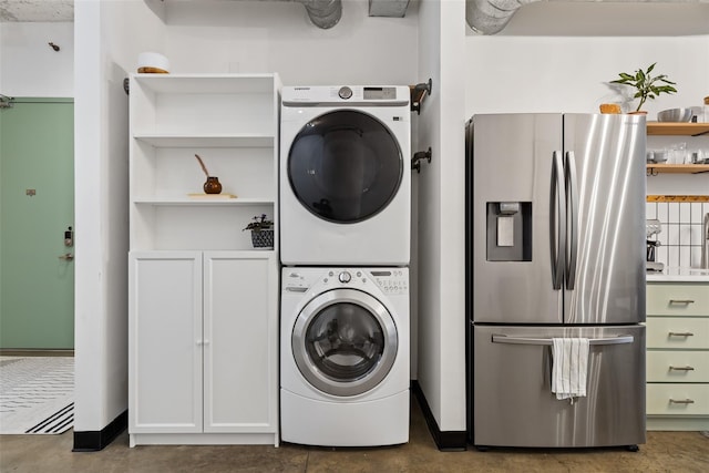 clothes washing area featuring cabinets and stacked washer / drying machine