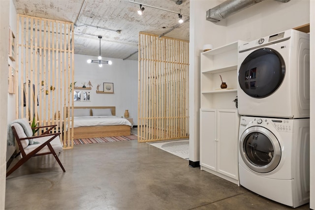 washroom featuring stacked washing maching and dryer and a notable chandelier