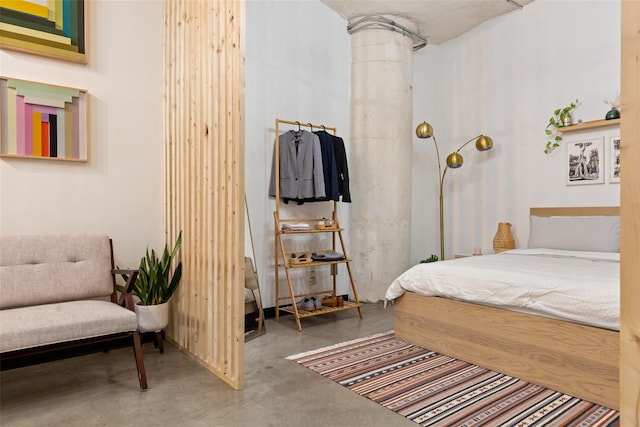 bedroom featuring decorative columns and concrete flooring