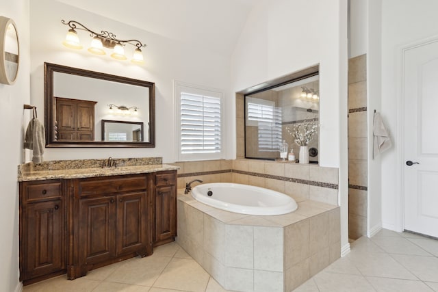 bathroom featuring a relaxing tiled tub, vanity, lofted ceiling, and tile patterned flooring