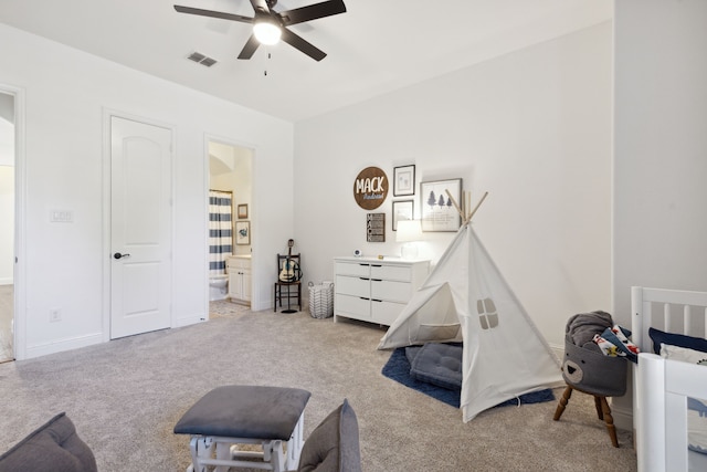 bedroom featuring ceiling fan, ensuite bathroom, and light colored carpet