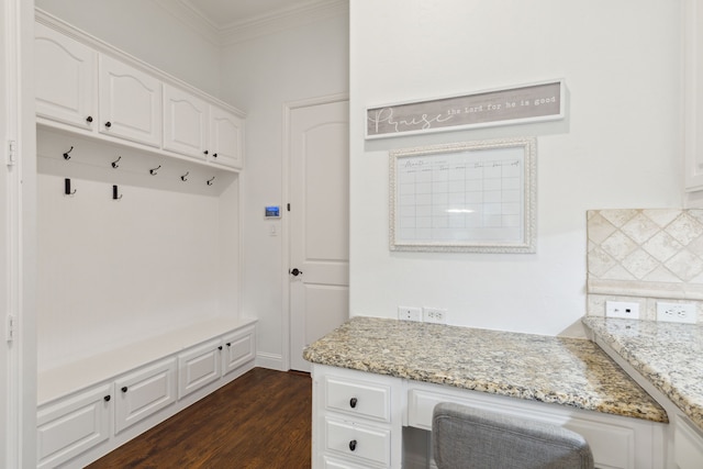 mudroom with crown molding, dark hardwood / wood-style floors, and built in desk