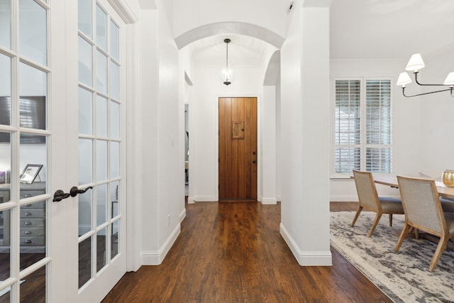 corridor with crown molding, an inviting chandelier, dark hardwood / wood-style floors, and french doors