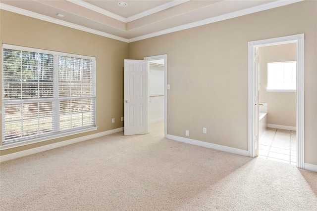 unfurnished bedroom featuring a spacious closet, ensuite bath, light carpet, a raised ceiling, and crown molding