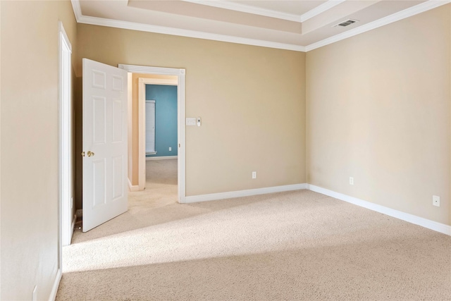 empty room featuring carpet, ornamental molding, and a tray ceiling