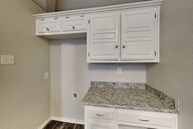 kitchen featuring dark wood-type flooring, light stone countertops, and white cabinets