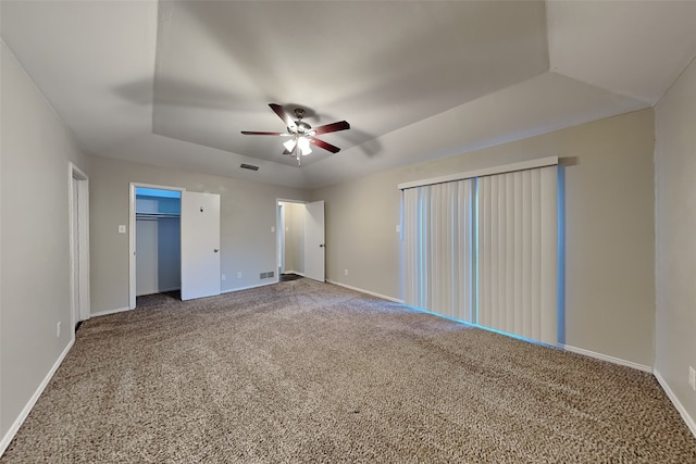 unfurnished bedroom featuring ceiling fan, a tray ceiling, and carpet flooring