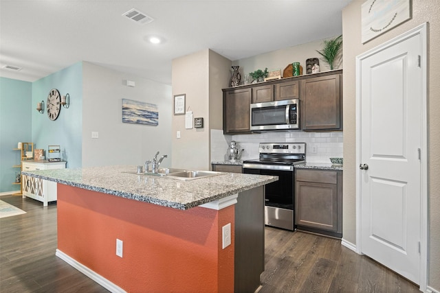 kitchen with a kitchen island with sink, sink, dark hardwood / wood-style flooring, backsplash, and stainless steel appliances