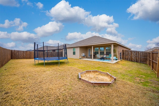 rear view of house featuring a trampoline, a patio area, and a lawn